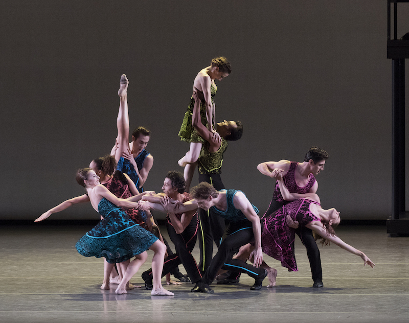 A mass of colorfully colored dancers strike virtuosic poses. 